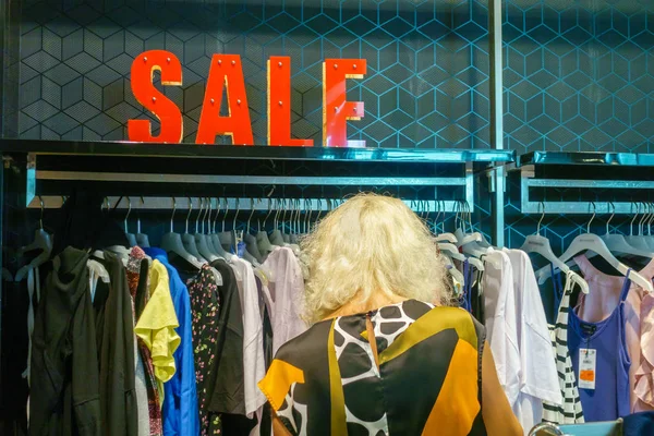 Mulher escolhendo roupas em uma loja de roupas, conceito de venda — Fotografia de Stock