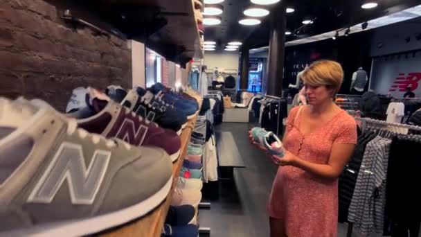 在第五大道的公司商店选择新的平衡运动鞋的妇女 — 图库视频影像