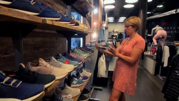 Donna che sceglie scarpe da ginnastica New Balance nel negozio aziendale sulla 5th Avenue — Video Stock