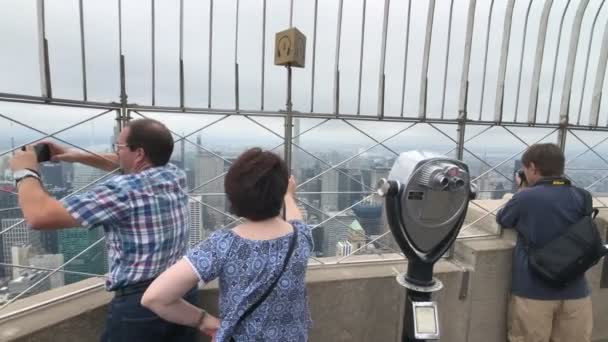 Bezoekers observeren van Manhattan stadsgezicht op Empire State building observatie dek — Stockvideo