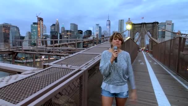 ブルックリン橋の上を歩く若い女性テレビ レポーターの放送は — ストック動画