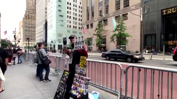 Hombre vendiendo insignias y recuerdos anti-Trump en el fondo de la torre Trump — Vídeo de stock