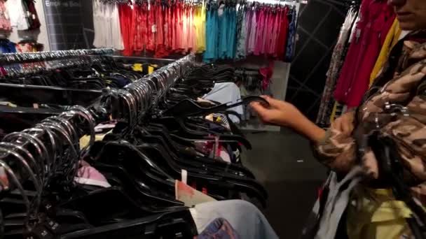 Jonge vrouw kleding in de kledingwinkel kiezen — Stockvideo