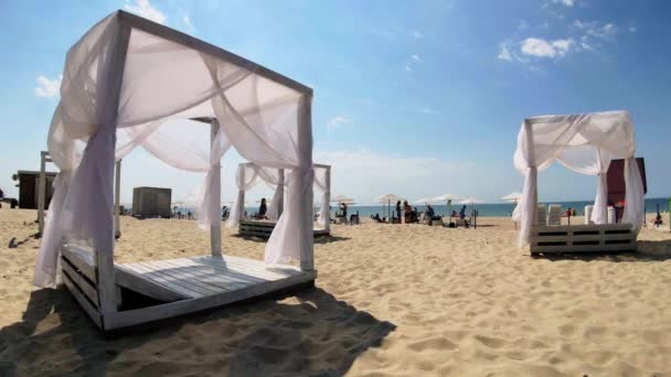 Люди загорают на обновленном пляже в солнечное время дня — стоковое видео