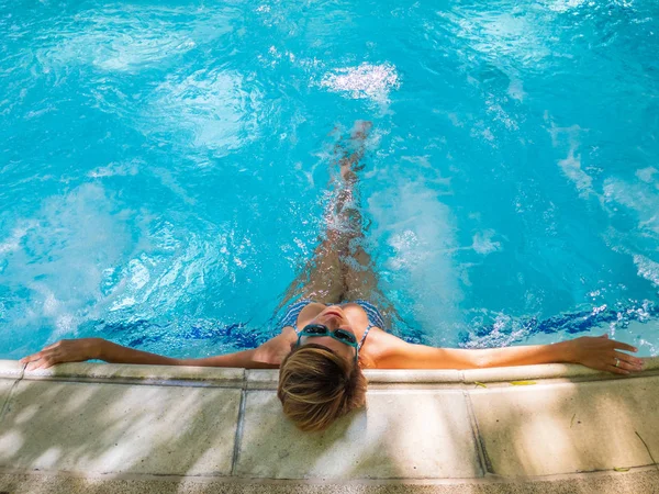 Jovem mulher bronzeando na piscina — Fotografia de Stock