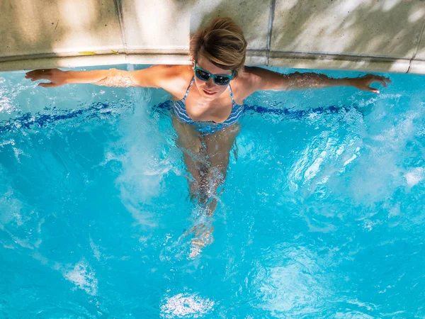 Mujer joven bronceándose en la piscina — Foto de Stock