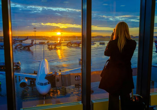 La mujer está de pie junto a la ventana en el aeropuerto —  Fotos de Stock