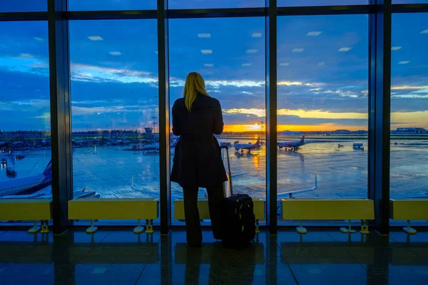 La mujer está de pie junto a la ventana en el aeropuerto —  Fotos de Stock