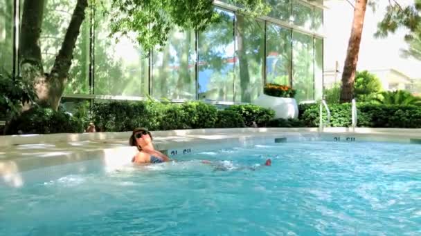 Junge Frau bräunt sich im Pool — Stockvideo
