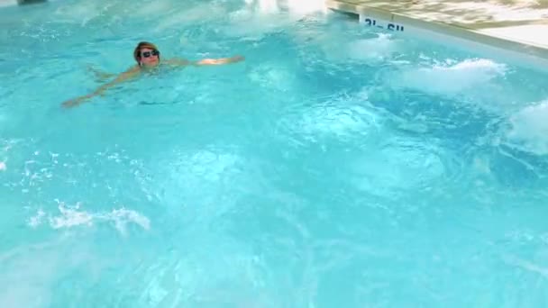 Mujer joven bronceándose en la piscina — Vídeo de stock