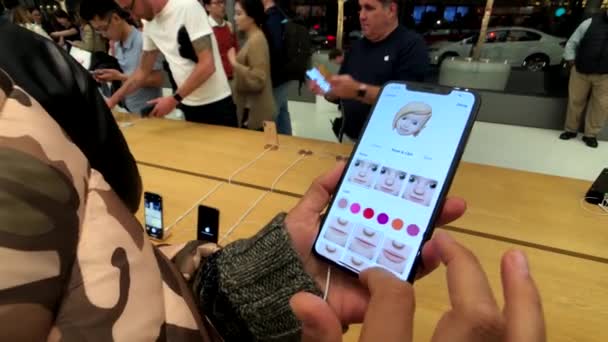 Kvinna som testar nya modellen Iphone Xs Max på Apple store, försöker skapa animoji — Stockvideo