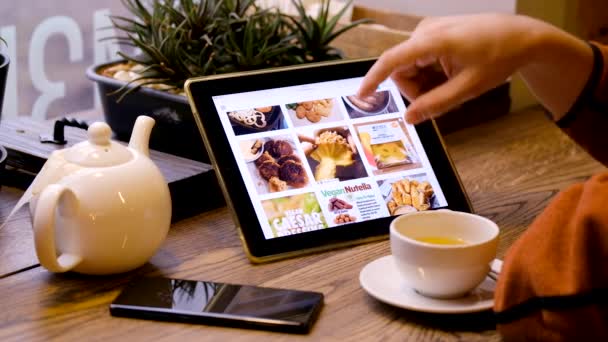 Άνθρωπος ψάχνει για φωτογραφίες από υγιή ακατέργαστη τροφή χρησιμοποιώντας tablet PC — Αρχείο Βίντεο