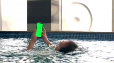 Havuzda akıllı telefon kullanan orta yaş adam