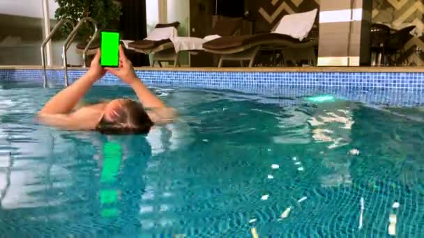 Мужчина средних лет использует смартфон в бассейне — стоковое видео