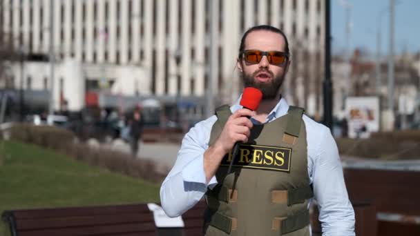 Тележурналист ведет репортаж из зоны конфликта — стоковое видео