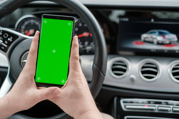 Man using smartphone on the background of a luxury class car dashboard