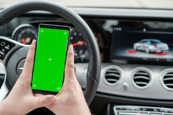 Man using smartphone on the background of a luxury class car dashboard