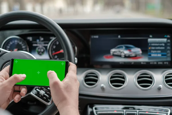 Homem usando smartphone no fundo de um painel de luxo classe carro — Fotografia de Stock