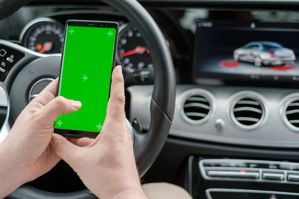 Homme utilisant un smartphone sur le fond d'un tableau de bord de voiture de classe de luxe — Photo