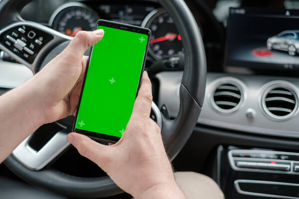 Man using smartphone on the background of a luxury class car dashboard