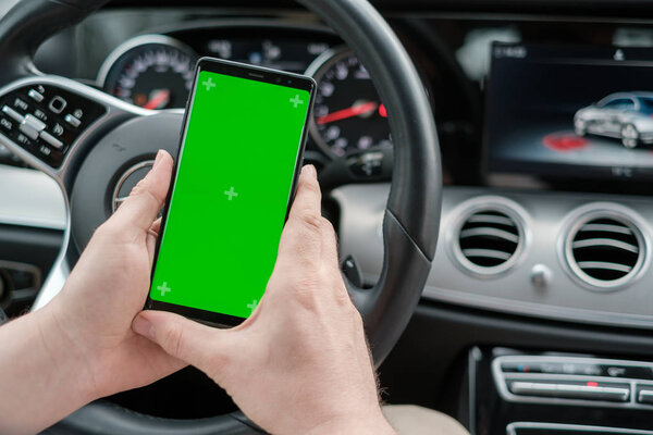 Man using smartphone on the background of a luxury class car dashboard