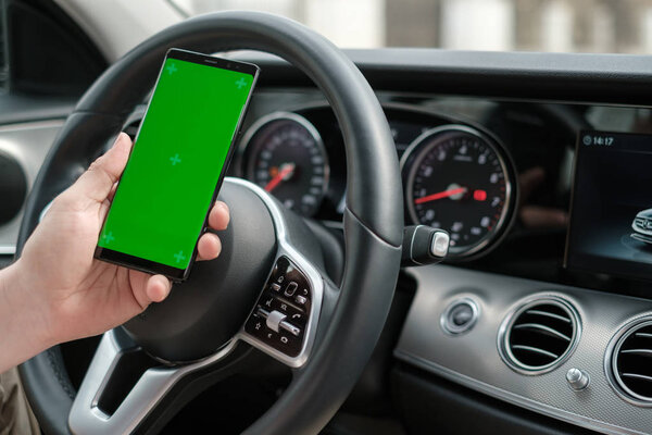 Man using smartphone on the background of a luxury class car dashboard