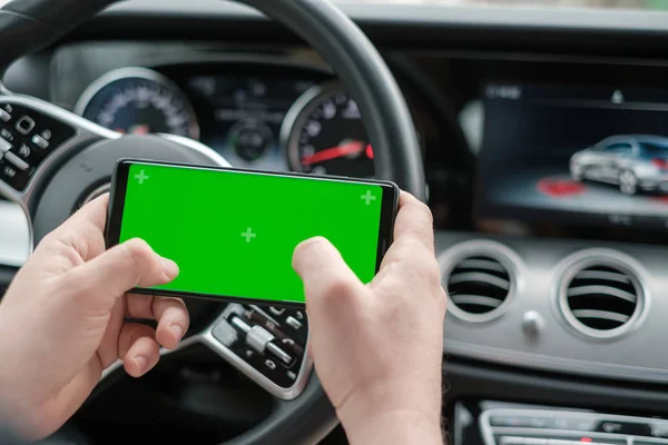 高級車のダッシュボードの背景にスマートフォンを使用している男性 — ストック写真