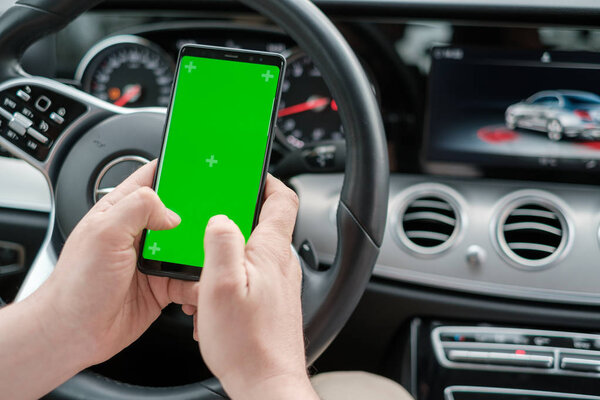 Man using smartphone on the background of a luxury class car dashboard