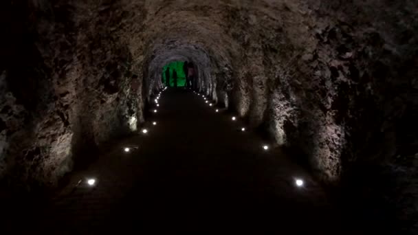 Туристы ходят по пещерному туннелю — стоковое видео