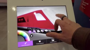 Dokunmatik ekranlı bir tablette gelecekteki trenlerin rengini seçen sergi ziyaretçisi