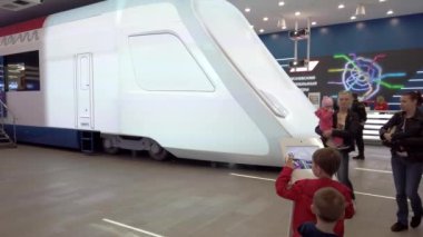 Dokunmatik ekranlı bir tablette gelecekteki trenlerin rengini seçen sergi ziyaretçisi