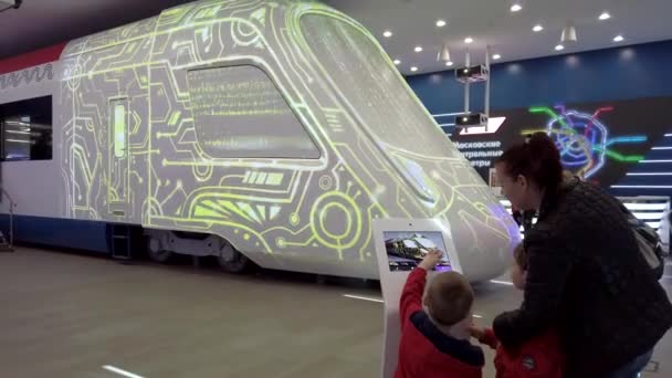 터치 스크린이 있는 태블릿에서 미래의 열차의 색을 선택하는 전시 관람객 — 비디오
