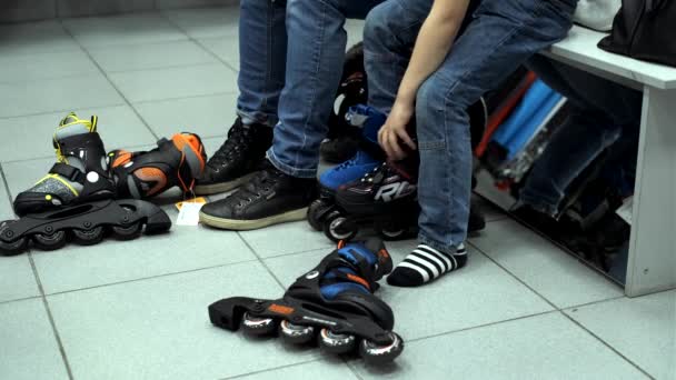 Madre e hijo se prueban zapatos deportivos y patines en una tienda de deportes — Vídeos de Stock