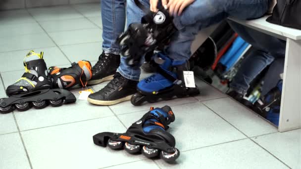 Moeder en zoon proberen op sportschoenen en rolschaatsen in een sportwinkel — Stockvideo