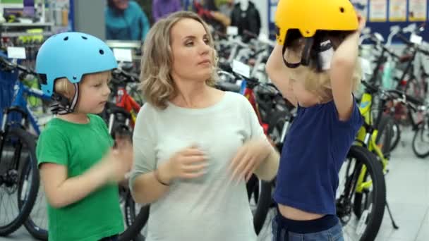 Mother choosing bicycle helmet for sons — Stock Video