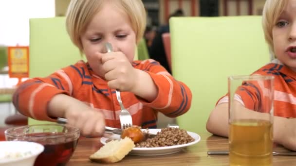 Hermanos chicos almorzan en la cocina — Vídeos de Stock