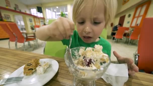 Menino comendo sobremesa na mesa na cozinha — Vídeo de Stock