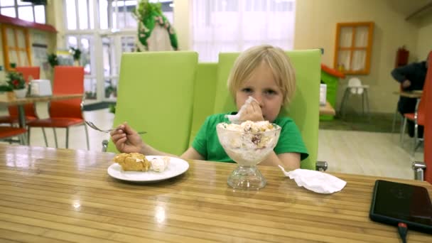 Niño comiendo postre en la mesa de la cocina — Vídeos de Stock