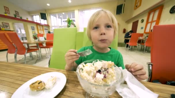 Niño comiendo postre en la mesa de la cocina — Vídeos de Stock