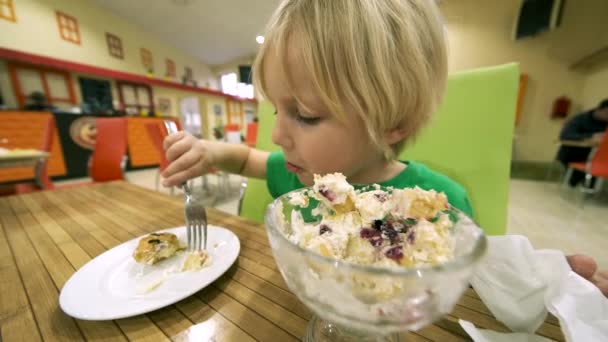 Niño comiendo postre en la mesa de la cocina — Vídeo de stock