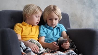 Kardeşler izliyor, oynuyor ya da akıllı telefondan bir şeyler öğreniyor.