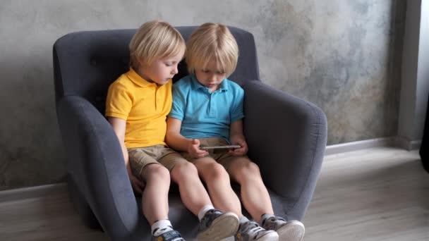 Irmãos estão assistindo ou jogando ou aprendendo algo em um smartphone — Vídeo de Stock