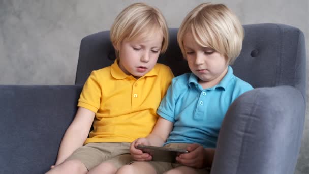 Los hermanos están viendo o jugando o aprendiendo algo en un teléfono inteligente — Vídeos de Stock