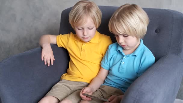 Irmãos estão assistindo ou jogando ou aprendendo algo em um smartphone — Vídeo de Stock