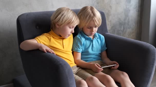 Irmãos estão assistindo ou jogando ou aprendendo algo em um smartphone — Vídeo de Stock