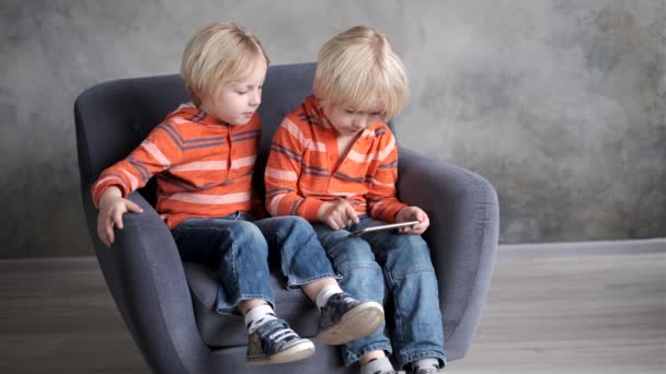 Bröder tittar på eller spelar eller lär sig något i en smartphone — Stockvideo