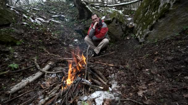 Mann mittleren Alters sitzt am Feuer im Wald — Stockvideo