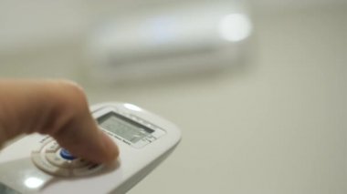 adam uzaktan kumanda ile klima sıcaklığını ayarlar