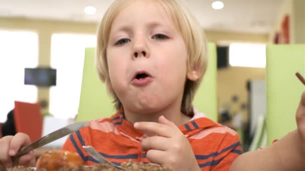 Pojke äter lunch vid bordet i köket — Stockvideo