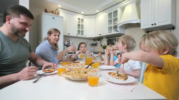 Familie mit Kindern isst Pizza am Tisch — Stockvideo